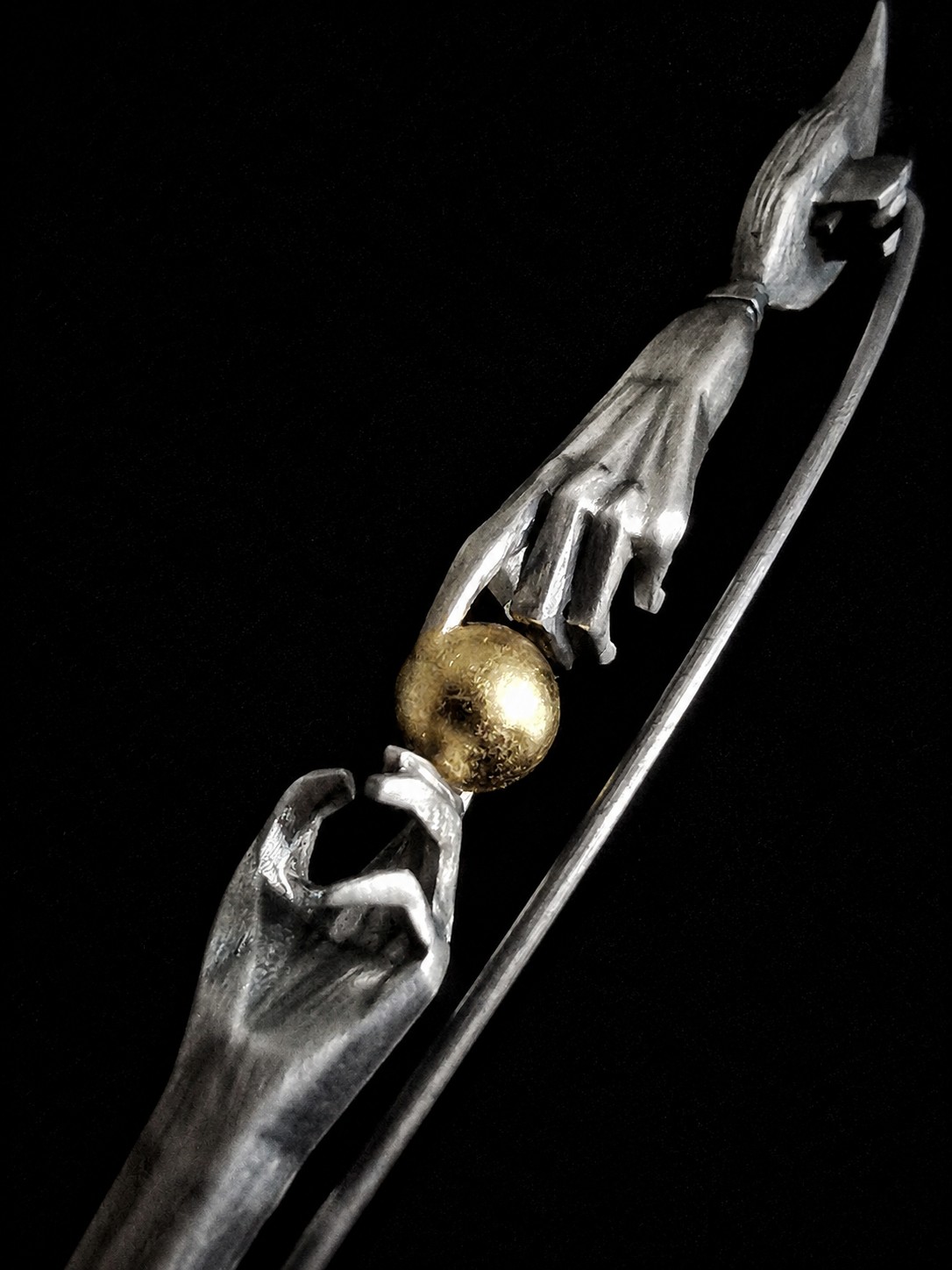 Commission paintbrush brooch, close-up of hands and golden sphere