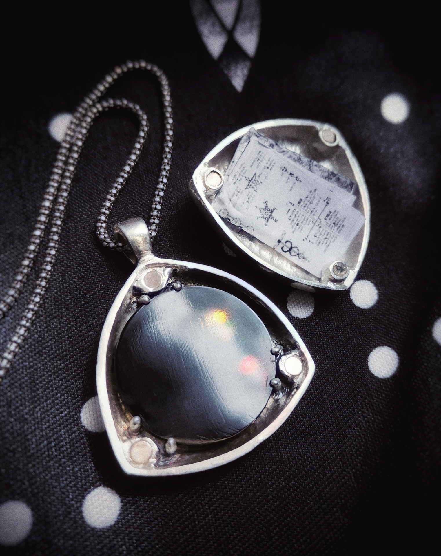 The Locket of the Future, opened revealing obsidian scrying mirror
